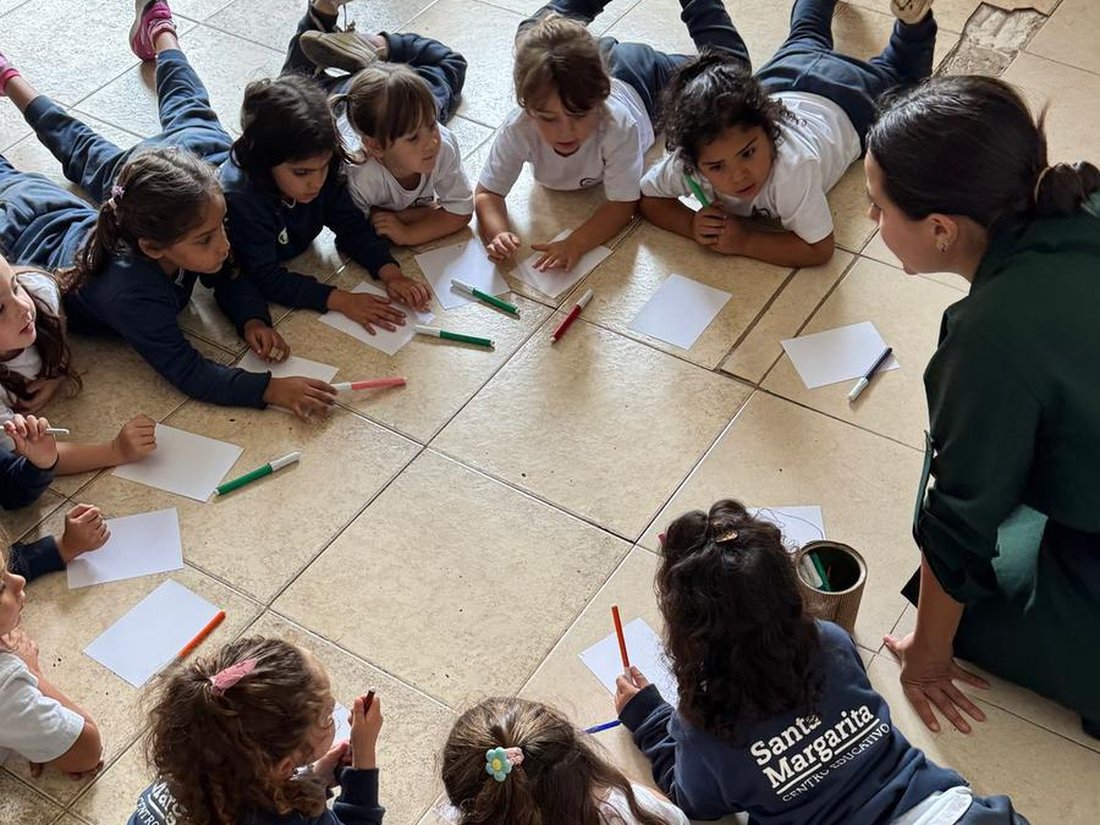 Alumnas y alumnos del Centro Educativo Santa Margarita dibujando en ronda en el piso, junto a su maestra